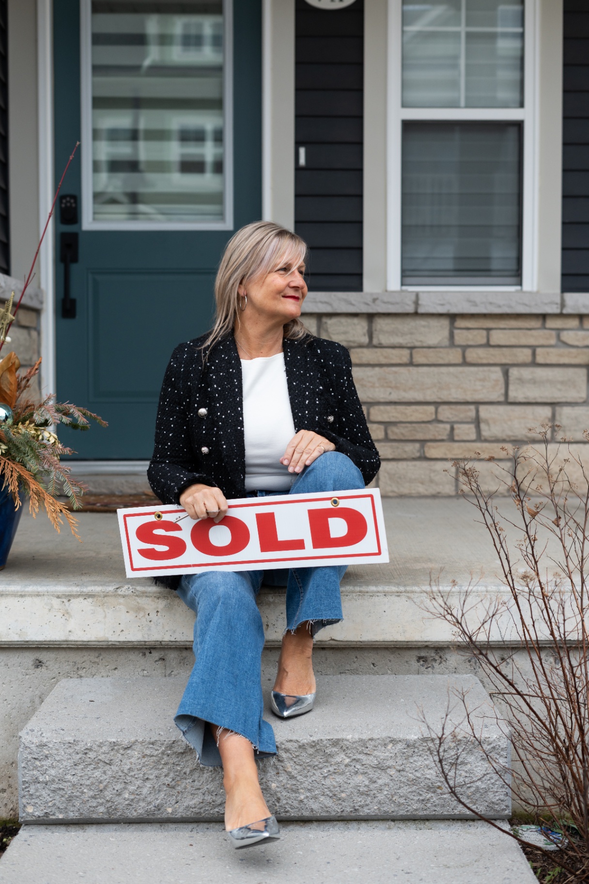 Karen Roy with a SOLD sign on a Niagara front porch